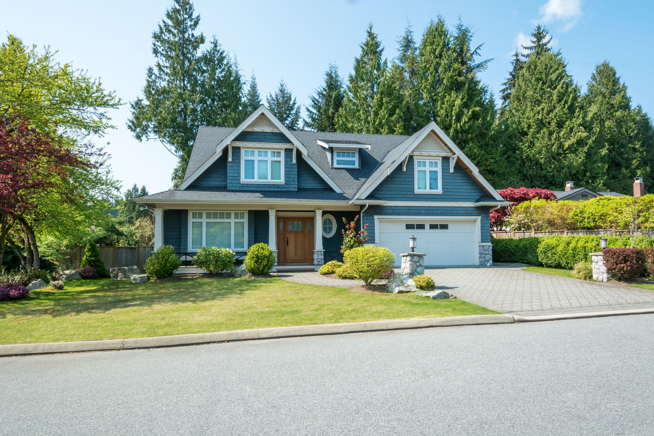Luxury blue house with beautiful landscaping on a sunny day. 