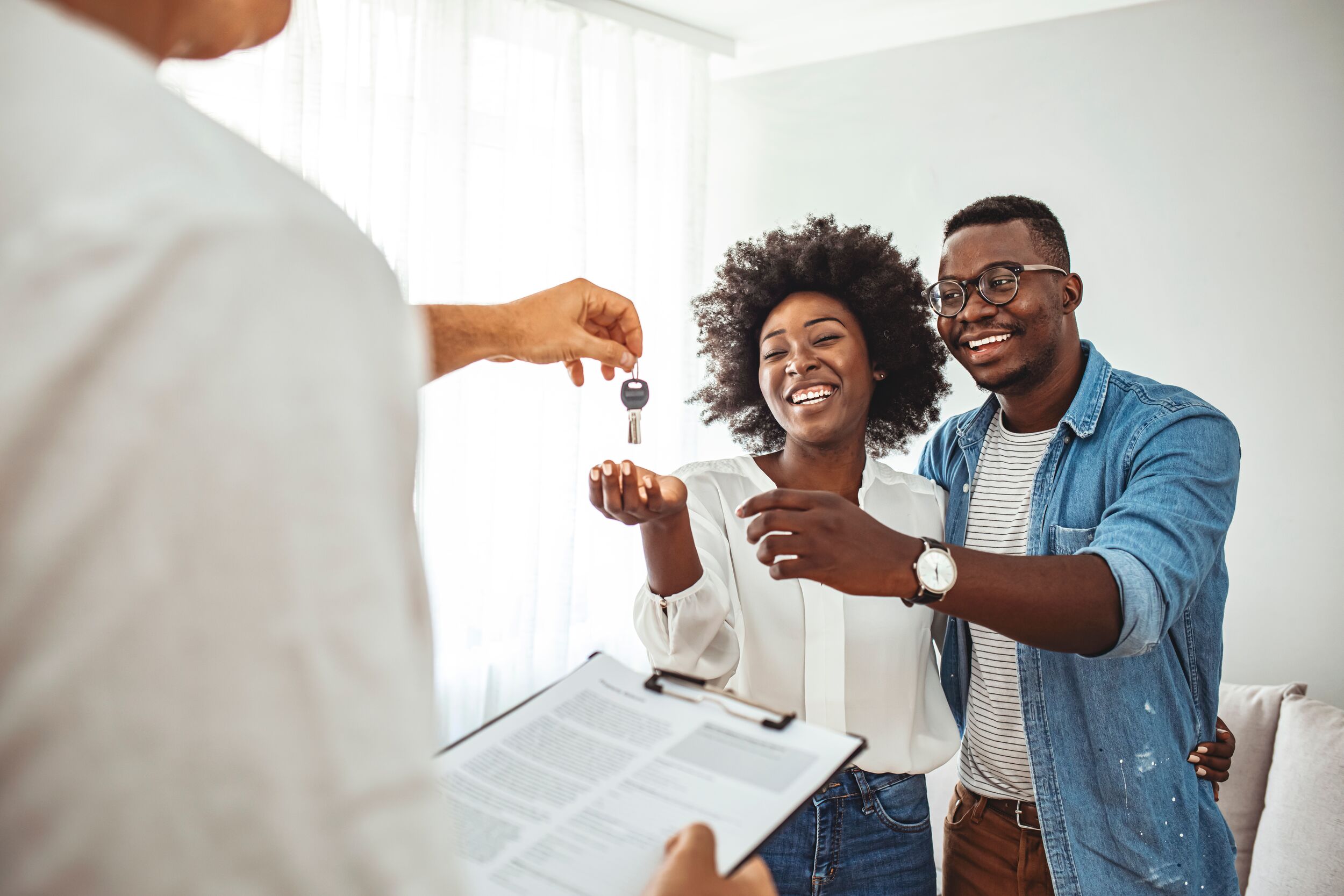 Smiling young couple receiving their new house keys from real estate agent.